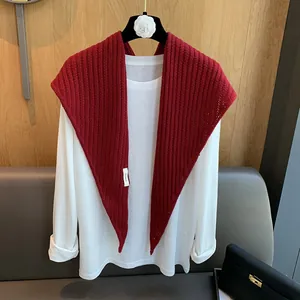 Détail de châle en laine bordeaux ajouré avec étiquette de marque et maille texturée