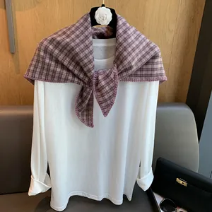 Detail of purple plaid woven triangle scarf showing fine edge stitching on white long sleeve tee