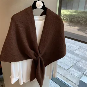 Detail of dark brown knitted wool blend shawl with a textured cross-loop closure design