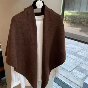 Detail of dark brown wool blend knit shawl with thick texture and asymmetric hemline