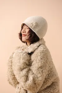 Close-up of a cream white knit beanie featuring an intricate side flower detail for women