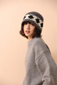Close-up of a warm 100% wool knit hat featuring a dark grey geometric heart pattern