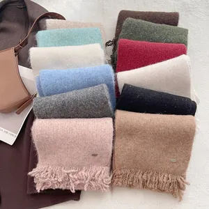 Macro shot of wool blend scarves showing soft texture and delicate tassel details