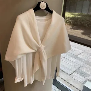 Detail of white cross-knit wool blend shawl with elegant twisted knot design and soft texture