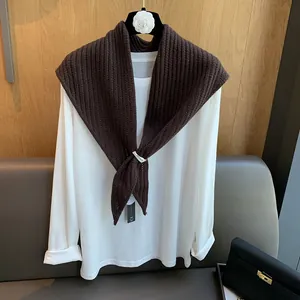 Détail du châle en tricot de laine marron foncé avec maille côtelée et clip de marque