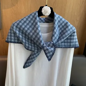 Close-up of blue plaid triangle scarf with refined blanket stitch edges on a hanger
