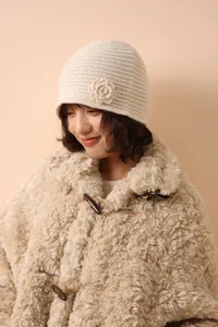 Close-up of cream knit beanie with handmade crochet flower detail and wool texture