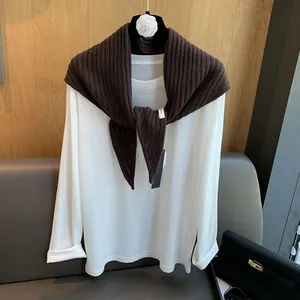 Détail d'un châle en laine sur un t-shirt blanc à manches longues sur un cintre chic