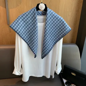 Close-up of blue and white checkered triangular scarf with dark blue stitched edges