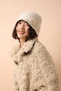 Detailed view of cream knit beanie featuring handmade floral crochet and soft wool texture