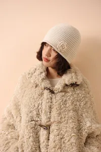 Detail of beige knit bucket hat with crochet flower decor and cozy wool texture