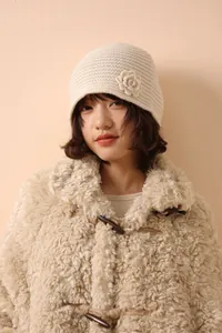 Detailed knit texture of beige crochet flower beanie with cozy wool coat style