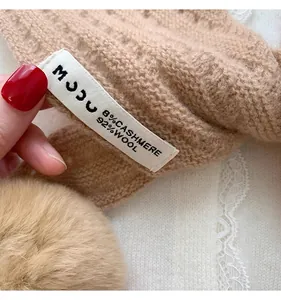 Detail showing wash label with 8% cashmere and 92% wool blend on camel knit scarf
