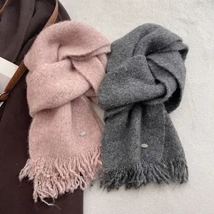 Close-up of thick wool blend knit scarf with tassels and metallic logo detail