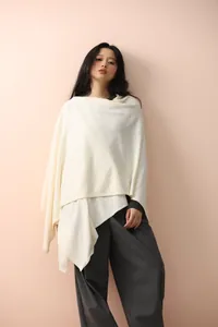 Detailed texture of ivory knit poncho shawl featuring premium draping and soft fabric
