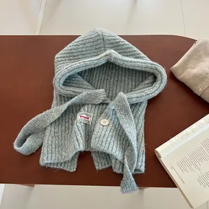 Detail of light blue knitted balaclava with single button and brand woven label