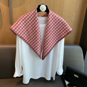 Detail of red and white plaid knit triangular scarf with deep red stitched edges