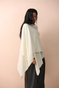 Detail of elegant cream knit shawl featuring soft texture and stylish asymmetric drape