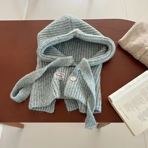 Detail of light blue knitted balaclava showing button closure and textured ribbing finish