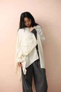 Close-up of ivory knit shawl texture with elegant drape on a grey wool suit