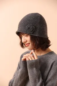 Detail of gray knitted beanie with handcrafted flower and textured hollow pattern