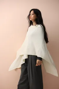 Detail of elegant cream knitted poncho shawl with fluid drape and premium fabric texture