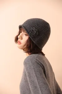 Detailed close-up of dark grey knit cloche hat with handcrafted crochet flower accent
