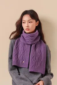 Detail van paarse merino wollen kabelgebreide sjaal met tweed textuur en metalen logo