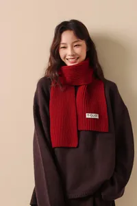 Close-up of red ribbed knit wool scarf texture with a minimal brand label detail