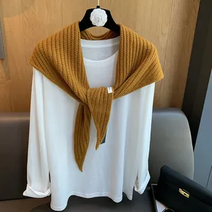Détail de l'écharpe en laine à texture côtelée avec étiquette sur un t-shirt blanc