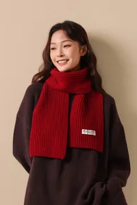 Detail of red wool knit scarf with brand label worn over a brown sweater
