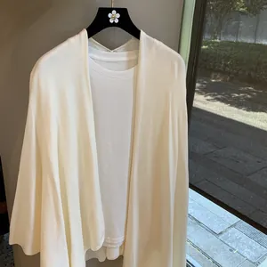 Detail of a thin white knit cardigan set featuring soft fabric and draped open front