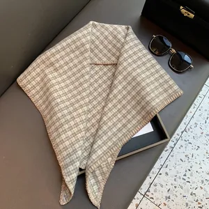 Detailed close-up of beige and brown plaid triangle scarf with clean stitched edges