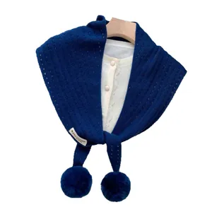 Navy blue wool cashmere knitted triangle scarf with cute pom-pom trim on white cardigan