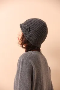 Detailed close-up of dark grey knitted floral beanie with 3D crochet flower detail