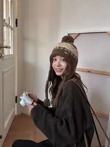 Détail d'un bonnet en maille avec protège-oreilles et pompon en marron et beige