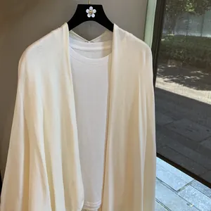 Detail showing the fine knitted texture and soft creamy white fabric of the women's shawl