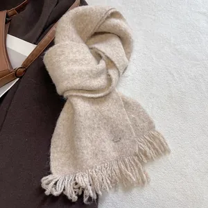Detail of oat beige wool blend scarf featuring soft tassels and a metallic logo tag