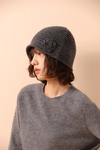 Detailed close-up of handmade dark grey crochet beanie with 3D floral accent