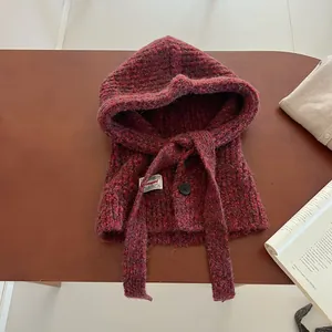 Close-up of red wool blend knit balaclava with decorative button and drawstring straps
