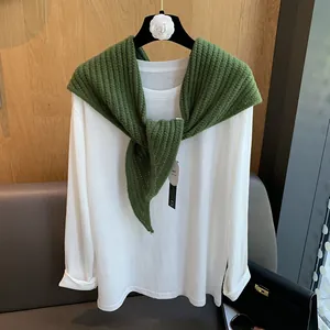 Détails de la texture du châle en laine verte et du t-shirt blanc en coton