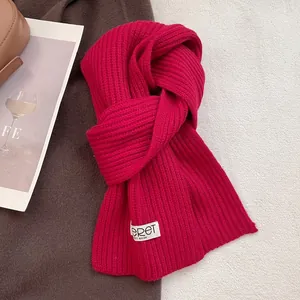 Close-up of thick fuchsia knit wool scarf with minimalist white logo label on cozy background