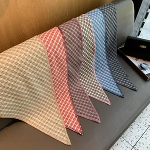 Detail of multi-color plaid triangle scarves featuring fine stitching on a leather bench