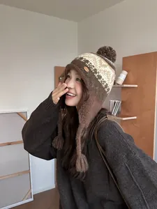 Vue détaillée du bonnet en tricot ethnique avec pompons bruns et motifs géométriques