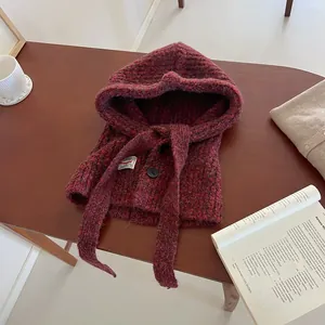 Close-up of wool blend knit texture and black button on dark red balaclava scarf