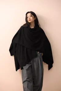 Detail of elegant black knitted shawl wrap showing soft texture and asymmetric drape