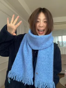 Close-up of light blue wool blend scarf featuring delicate sequins and tassel edges