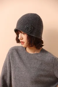 Detailed view of dark grey handmade crochet flower on a knit beanie hat for women