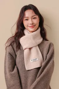 Detailed close-up of cream knit wool scarf with premium texture and woven label