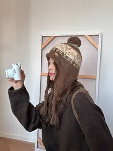 Détail du bonnet en tricot nordique vintage avec pompon et pompons tressés marron